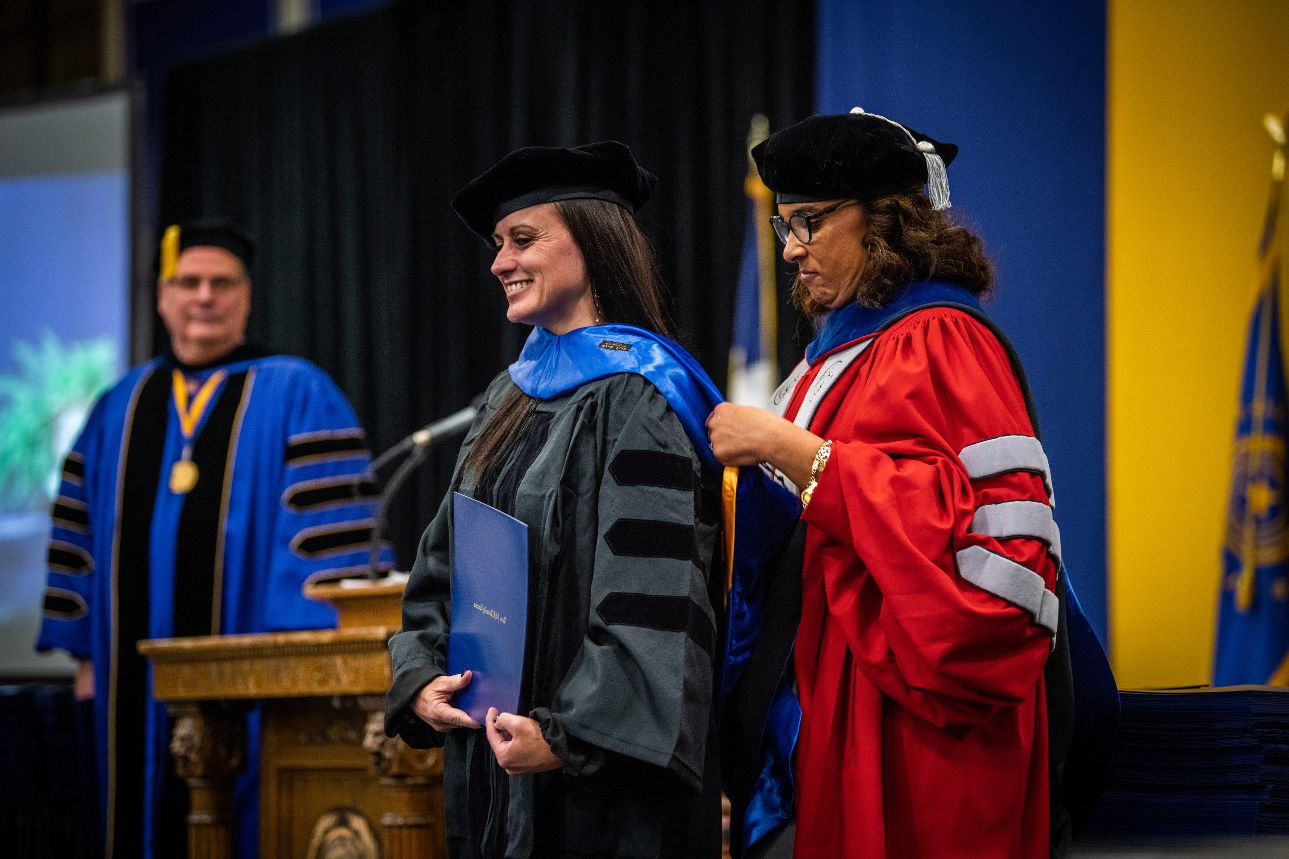 Female professor hooding a female graduate student at graduation.